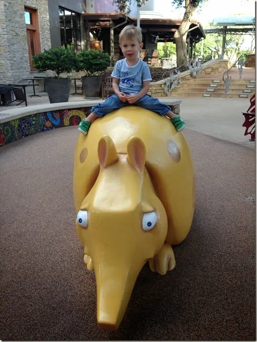 Child riding a giant armadillo statue at The Domain