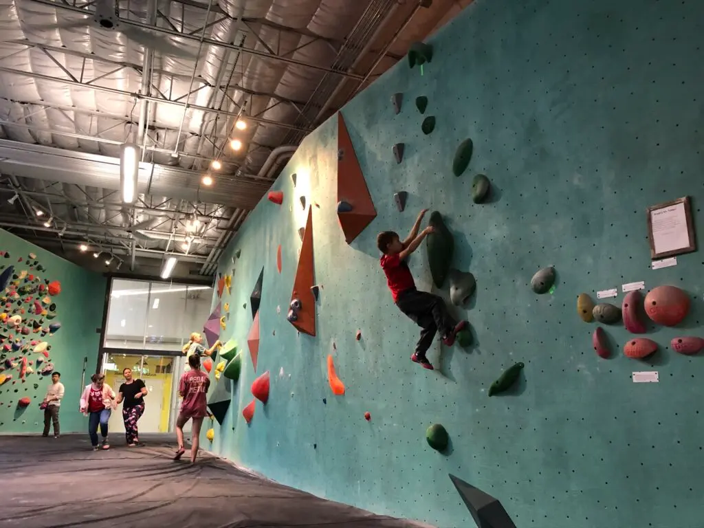 Kids climb across one of the climbing walls at Austin Bouldering Project