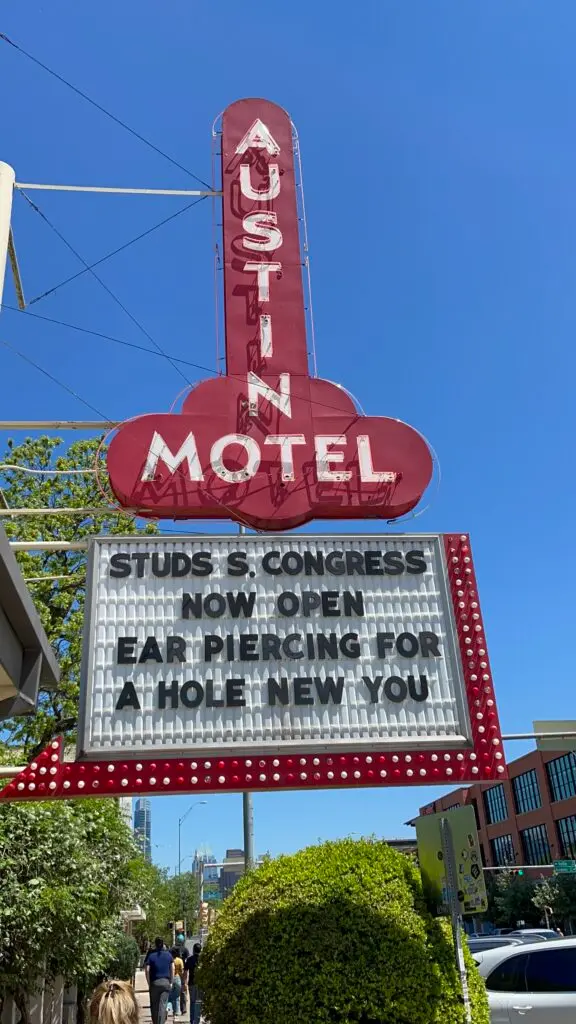 Austin Motel marquee stating "Studs South Congress Now Open Ear Piercing For A Hole New You"