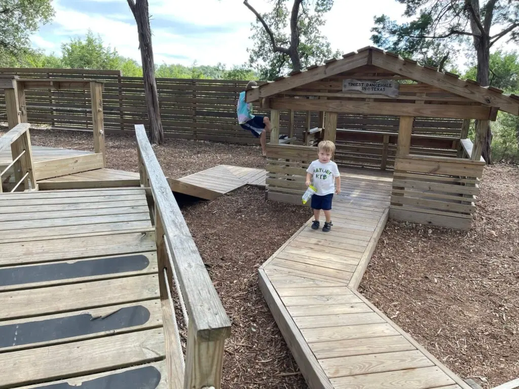 Children playing on the little wood cabin playground at The Shady Llama