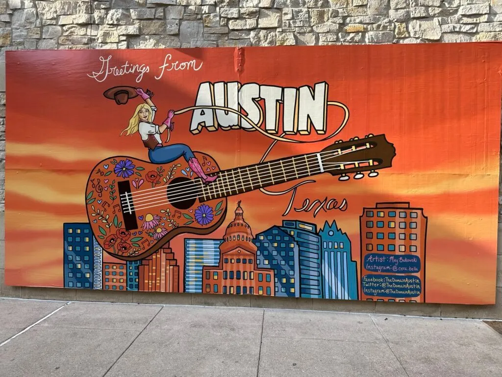 Greetings From Austin Texas mural with a woman riding a flying guitar at The Domain