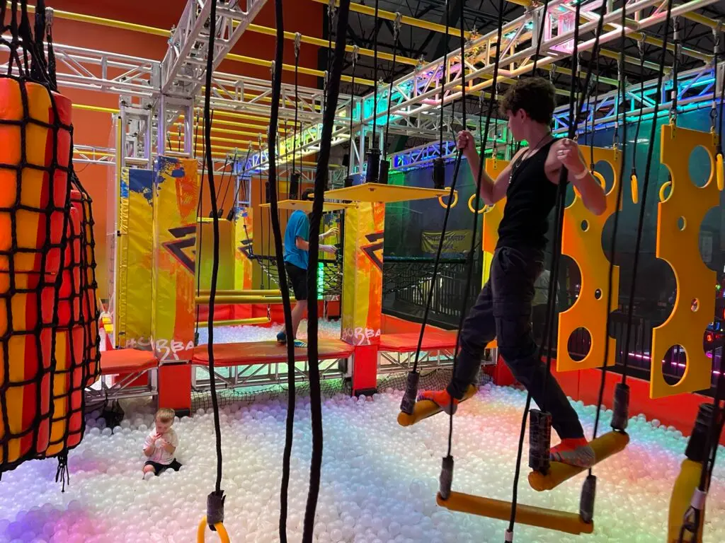 Kids swing across a giant ball pit at Urban Air