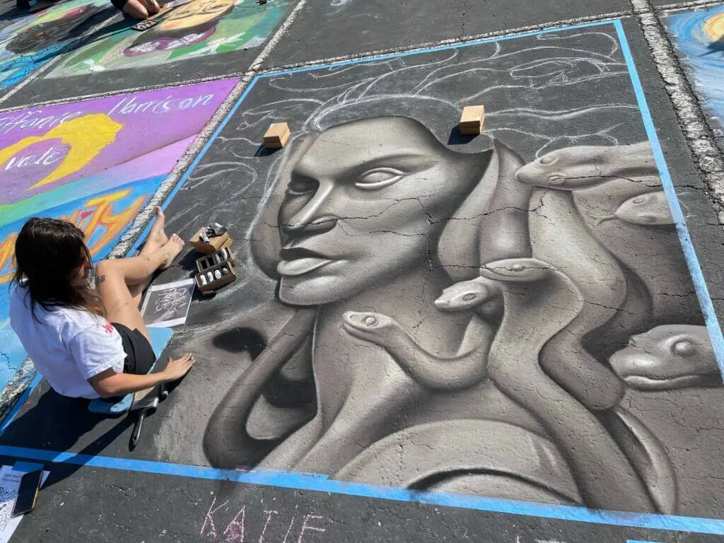 Artist creating a chalk art Medusa at Chalk Walk in Round Rock