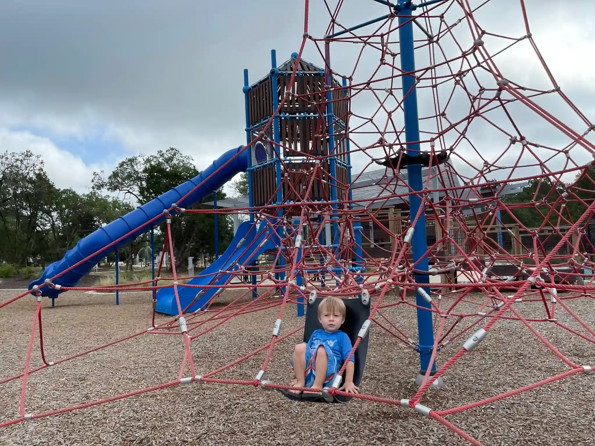 a child sits on a big playscape at lakewood park