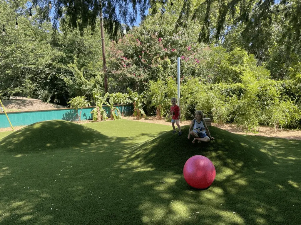 Ski Shores Cafe by Lake Austin turf mounds with two kiddos ready to roll around