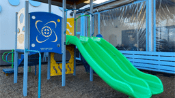 Outdoor playground slide next to a restaurant patio, great for families in Austin